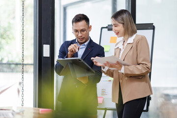 Asian businessman and businesswoman looking at laptop computer in the workplace office, Feeling happiness
