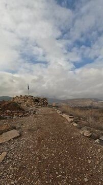 Ruins of the ancient fortress at Tel Hazor, a UNESCO World Heritage Site in northern Israel's Galilee, set against dramatic cloudy skies and lush natural surroundings.