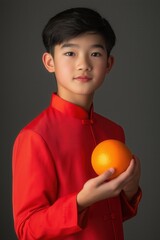 Asian Man in Red Traditional Attire Holding an Orange