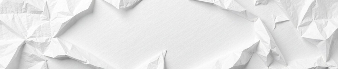 Crumpled paper sheet with scattered white crinkles, white background, torn paper