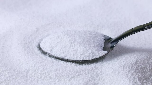 Taking white natural organic sweet Sorbitol sweetener granules in spoon close up. Sugar substitute concept