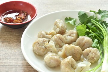 steamed fish dumpling with parsley and spring onion on plate dipping spicy sour sauce 