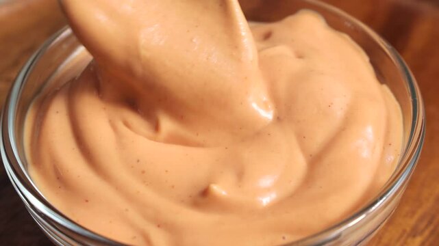 Homemade American burger sauce or thousand island dressing mixing and taking with a spoon in a glass bowl close up