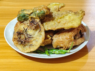 Gorengan, a traditional Indonesian street food consisting of tahu brontak, fried banana, bakwan, tempe mendoan, etc. Served with green chili.