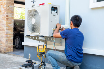 Male technician installing outdoor unit of air conditioner  to cool the household in the summer....
