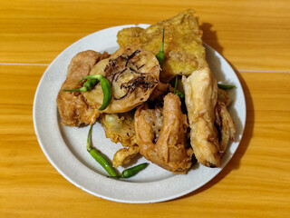 Gorengan, a traditional Indonesian street food consisting of tahu brontak, fried banana, bakwan, tempe mendoan, etc. Served with green chili.