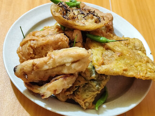 Gorengan, a traditional Indonesian street food consisting of tahu brontak, fried banana, bakwan, tempe mendoan, etc. Served with green chili.