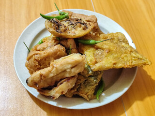 Gorengan, a traditional Indonesian street food consisting of tahu brontak, fried banana, bakwan, tempe mendoan, etc. Served with green chili.