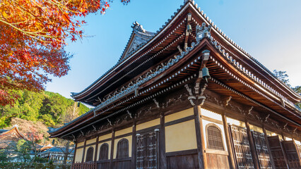 The Sanmon Gate of Nanzenji Temple with intricate wooden architecture and hanging bells. Clear blue sky and surrounding trees, Kyoto, Japan.