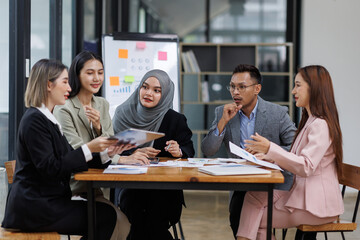 Happy asian business woman executive ceo leader discussing project management planning strategy working with diverse colleagues company team at office corporate board group meeting.
