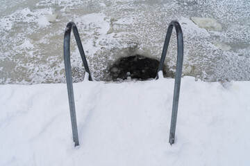 A ladder into an ice hole for winter swimming. Hardening, winter swimming, health, ice water, extreme, active lifestyle, traditions.