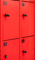 A row of modern bright red lockers with numbers are aligned in a straight line.