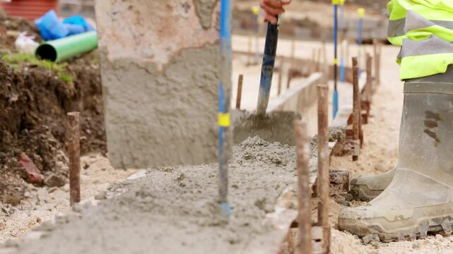 Workers pour fresh concrete into foundation molds at construction site