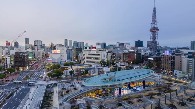 aerial city skyline timelapse view of the Nagoya city center with Nagoya TV Tower landmark building among highrise building and some traffic on street in sunset twilight color sky