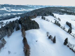 aerial photography of a snowy landscape with spruce and fir forest in alpine landscape of Vorarlberg next to Sulzberg, Austria