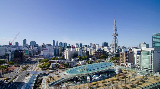 aerial city skyline timelapse view of the Nagoya city center with Nagoya TV Tower landmark building among highrise building and some traffic on street in winter daytime with clear blue sky