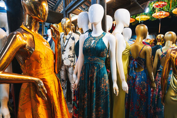 Fototapeta premium A group of mannequins in bright elegant dresses stands outside a women's clothing store