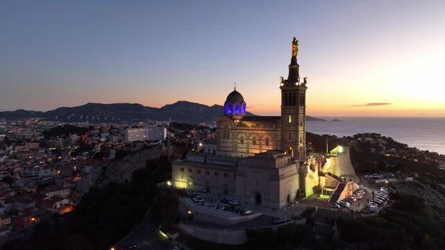 aerial shot of Marseille cathedral at night illuminated, drone view of Notre Dame de la Garde in France, travel in French Riviera