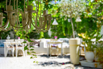 Greek restaurant tables under a vine canopy providing shady areas for people to sit. Alfresco dining cuisine.