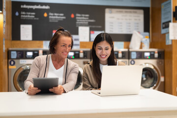 Two women working on a computer in laundry shop