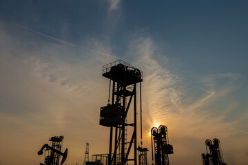 A silhouette of a pumping unit working in the evening