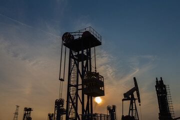 A silhouette of a pumping unit working in the evening
