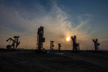 A silhouette of a pumping unit working in the evening