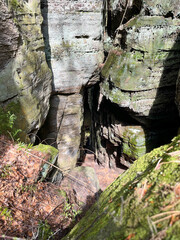 Cave entrance between rocks in the forest in the Mullerthal region, Luxembourg.