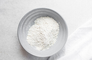 overhead view of All purpose flour in a bowl, top view of baking flour in a ceramic bowl
