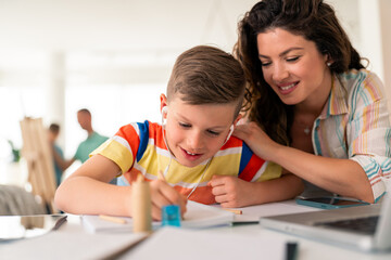 Fototapeta premium Supportive Mother Helps Young Student Complete Homework Assignment At Home Table