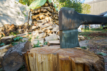 Large log is being chopped with an axe. The log is on the ground and the axe is in the air