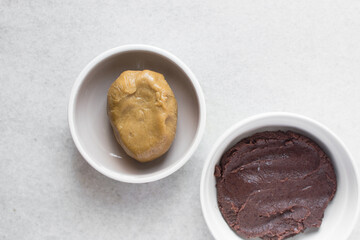 Overhead view of mooncake dough and red bean paste in a white plate, top view of mooncake dough and sweet adzuki bean paste in a white plate, process of making mooncakes