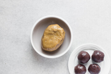 Overhead view of mooncake dough and red bean paste in a white plate, top view of mooncake dough and sweet adzuki bean paste in a white plate, process of making mooncakes