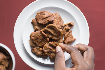 Overhead view of kuli-kuli on a white plate, top view of nigerian groundnut cakes on a plate, fresh homemade nigerian kulikuli on a ceramic plate