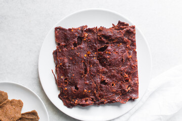 Overhead view of Nigerian kilishi on a white plate, top view of nigerian spicy beef jerky, flatlay of dried beef suya