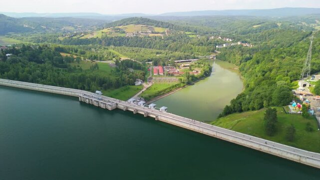 Aerial view of Solina dam surrounded by lush green countryside and calm waters.