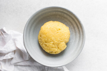 overhead view of Eba in a grey bowl, Nigerian garri, top view of yellow garri on a grey plate