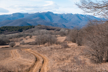 Winter mountain valley with dirt road and high mountains in the background