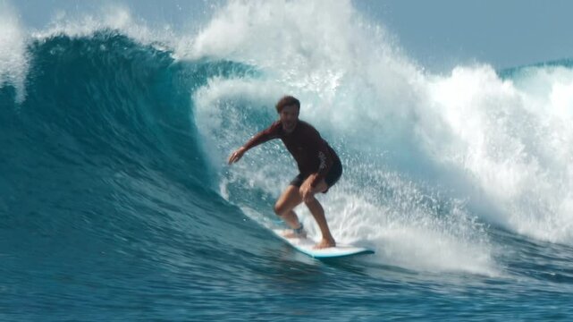 Surfer rides a wave in a tropical ocean. Maldives