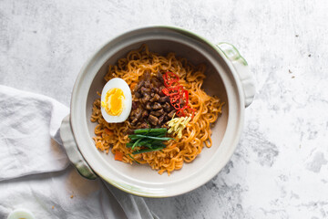 Overhead view of Spicy instant noodles in a claypot, top view of spicy ramen noodles with soft boiled egg in a donabe