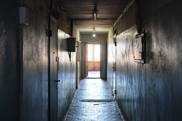 A dimly lit corridor stretches ahead, leading to an open doorway that invites exploration