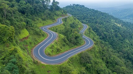 Fototapeta premium Aerial view of winding road through lush green mountain landscape.