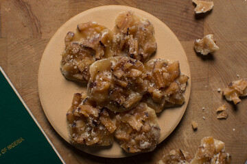 Overhead view of nigerian coconut candy on a wood countertop, top view of candied coconuts discs, flatlay of bukayo candy or coconut drops