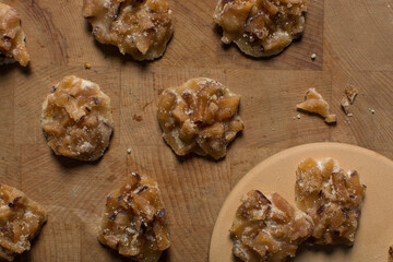 Overhead view of nigerian coconut candy on a wood countertop, top view of candied coconuts discs, flatlay of bukayo candy or coconut drops