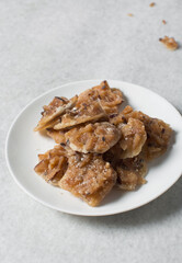 Overhead view of nigerian coconut candy on a white plate, top view of candied coconuts discs, flatlay of bukayo candy or coconut drops