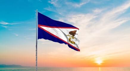 Waving flag of American Samoa against the background of a sunset or sunrise. American American Samoa with flying flag beauty. American Samoa Flag with Sunset Background