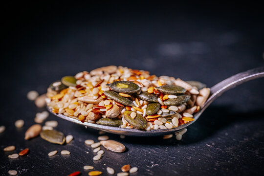 A vibrant close-up of a seed mix featuring pumpkin seeds, flaxseeds, sesame seeds, and sunflower seeds. The colorful textures highlight the variety and freshness of the seeds. - Powered by Adobe
