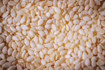 A macro shot of white sesame seeds showcasing their smooth texture and oval shape, commonly used in cooking and baking.