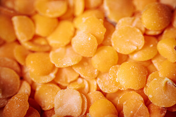 A close-up view of vibrant orange lentils, highlighting their smooth, flat texture and natural color. Ideal for showcasing healthy, plant-based food options.
