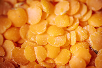 A close-up view of vibrant orange lentils, highlighting their smooth, flat texture and natural color. Ideal for showcasing healthy, plant-based food options.